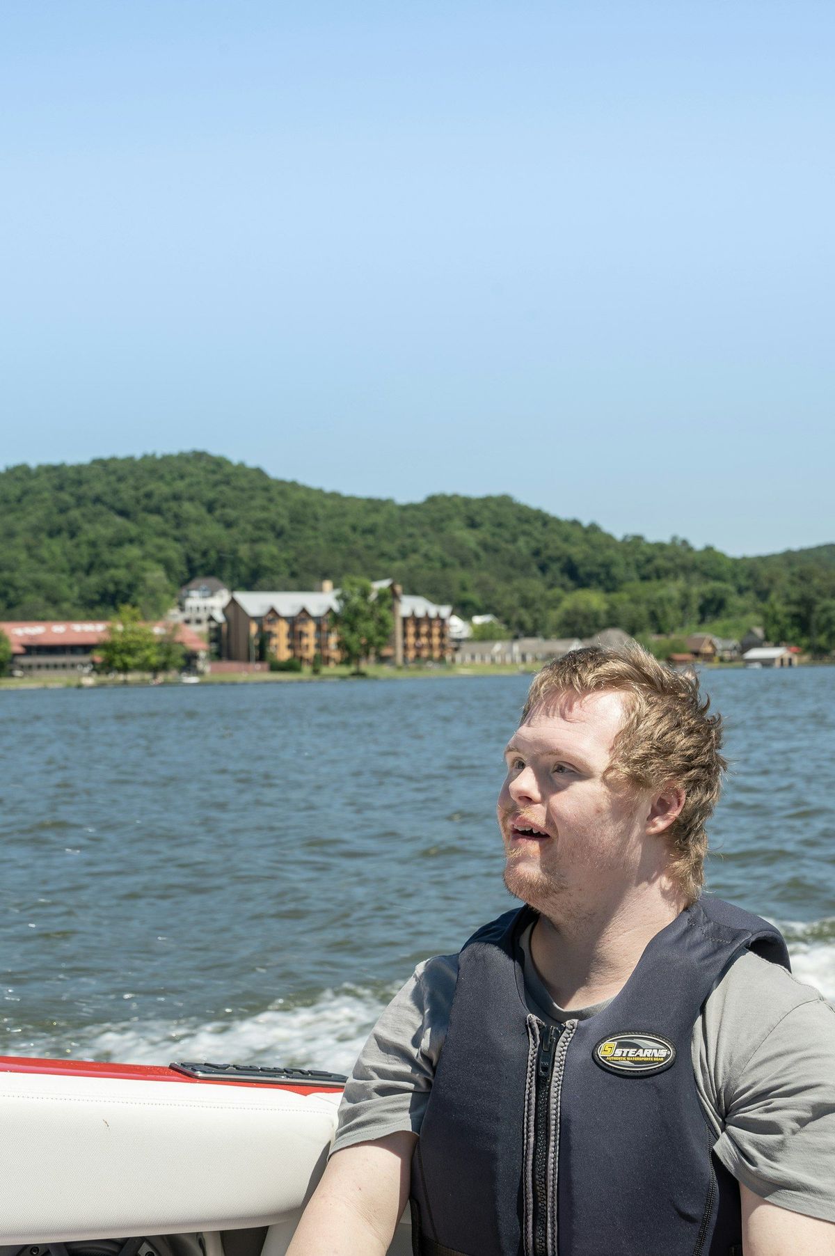 Young man with Down syndrome smiling on a boat ride across a lake