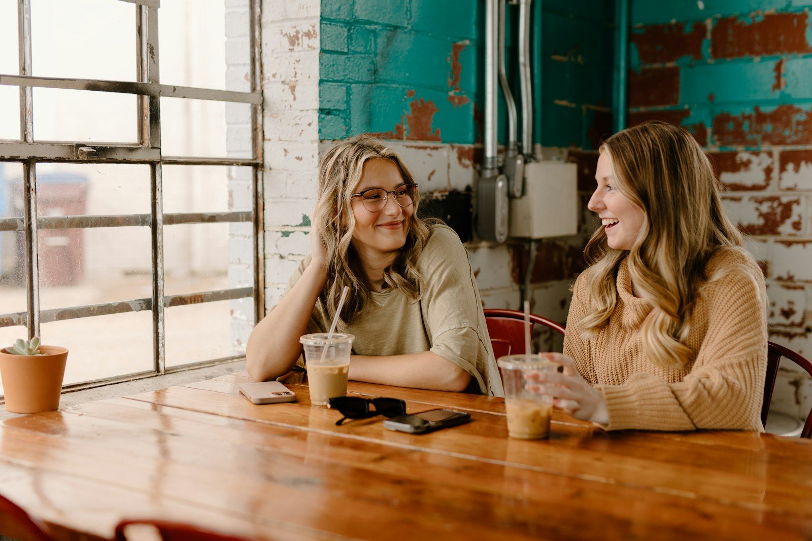 Two friends laughing together at a cafe table