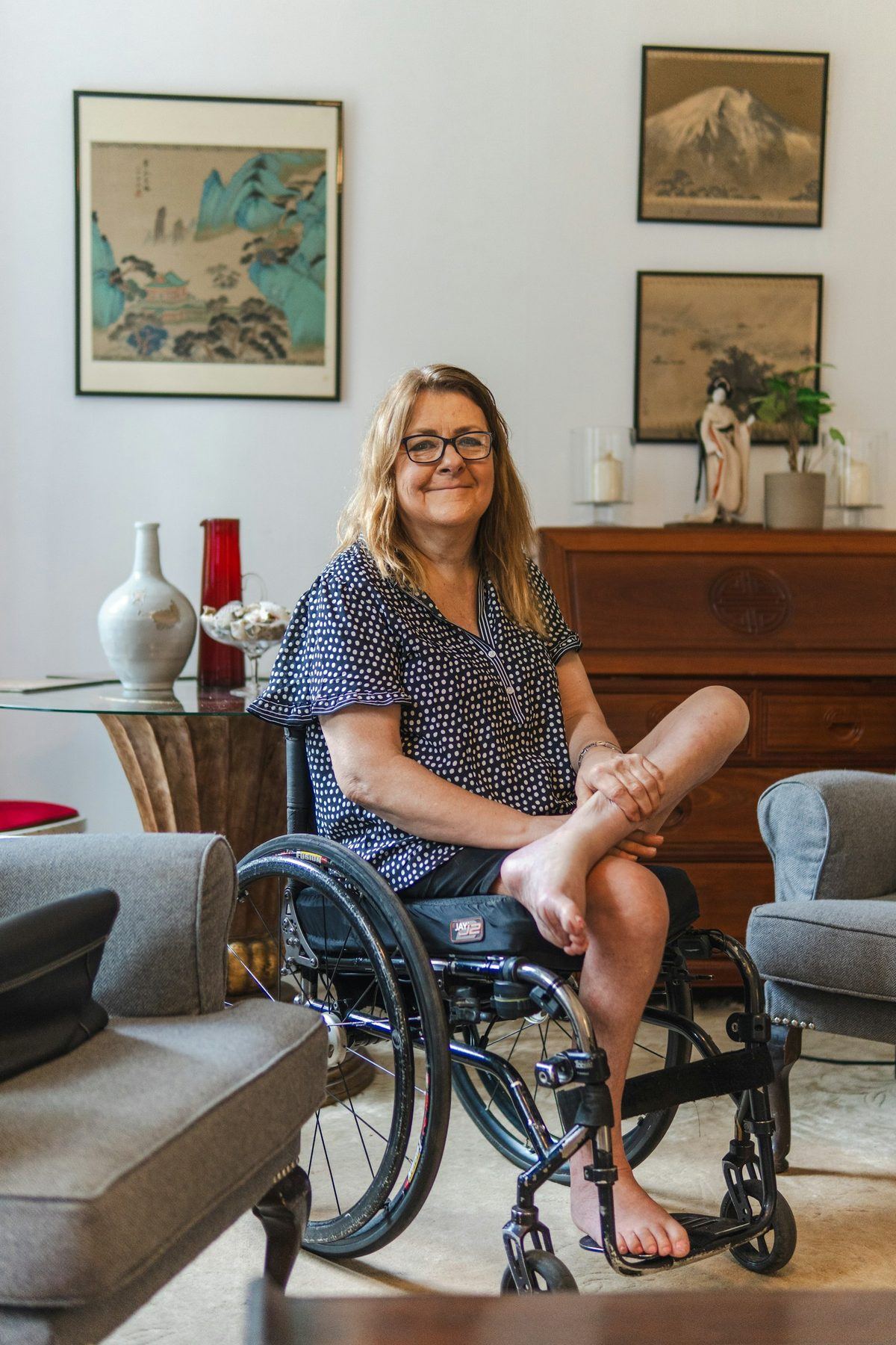 Woman smiling in her wheelchair in a bright living room
