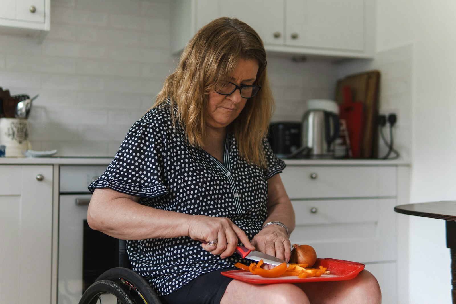 Woman in a wheelchair preparing vegetables in her kitchen