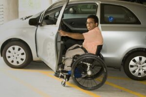 A man in a wheelchair getting into a car adapted for a driver with disability