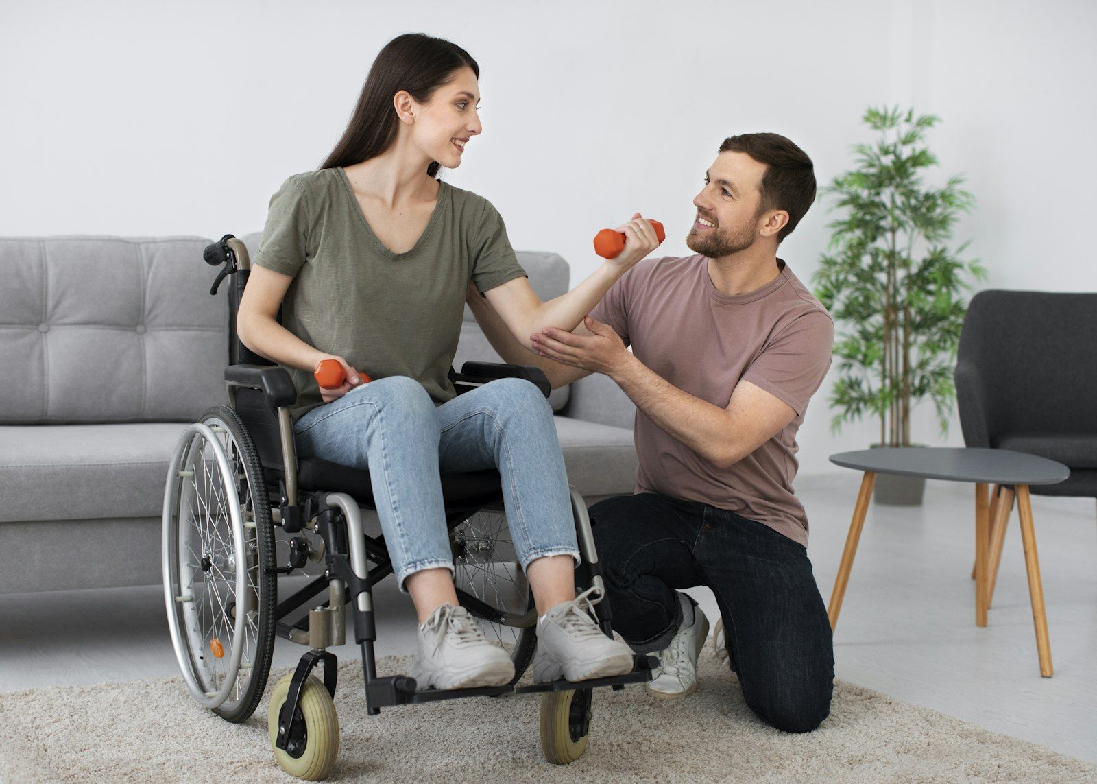 A support worker and a woman in a wheelchair doing an exercise together in a bright living room